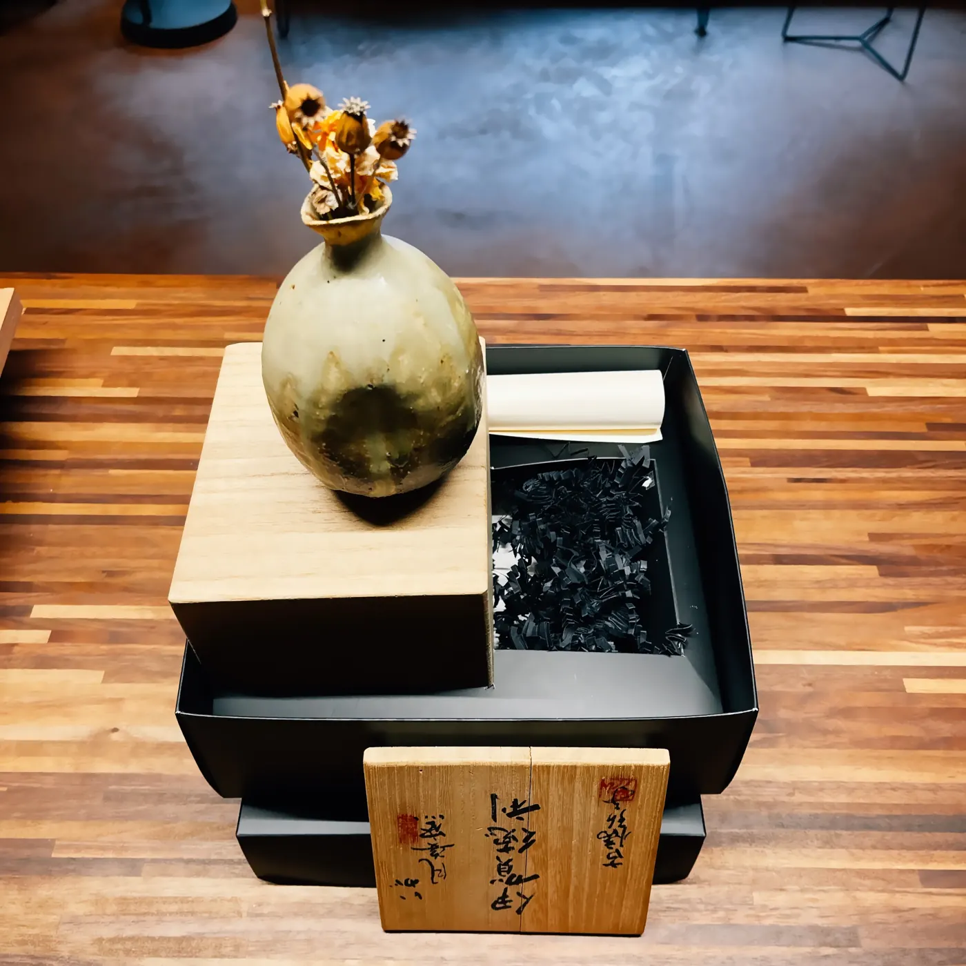 Le tokkuri restauré posé sur sa boîte en paulownia, le couvercle calligraphié appuyé devant.